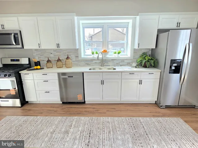 a view of a kitchen with white cabinets and wooden floor