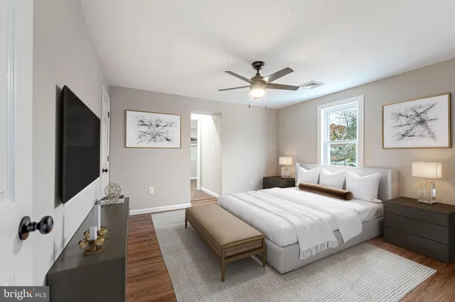 a bedroom with a large bed a flat tv screen and a chandelier