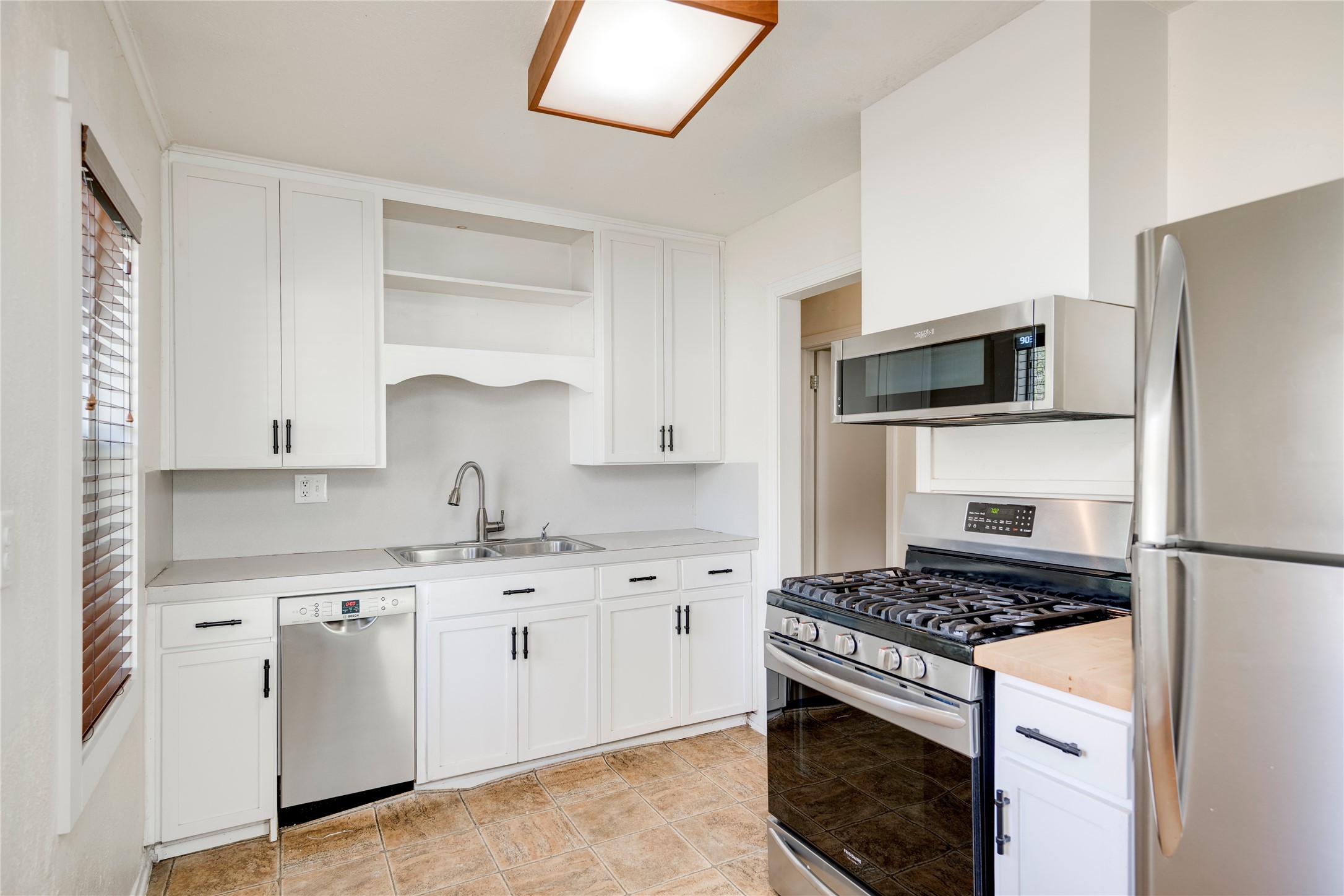 4804 Tanney Street Austin, TX 78721 - Photo 14 of 40 A well-equipped kitchen features white cabinetry and stainless steel appliances, offering functional style.
