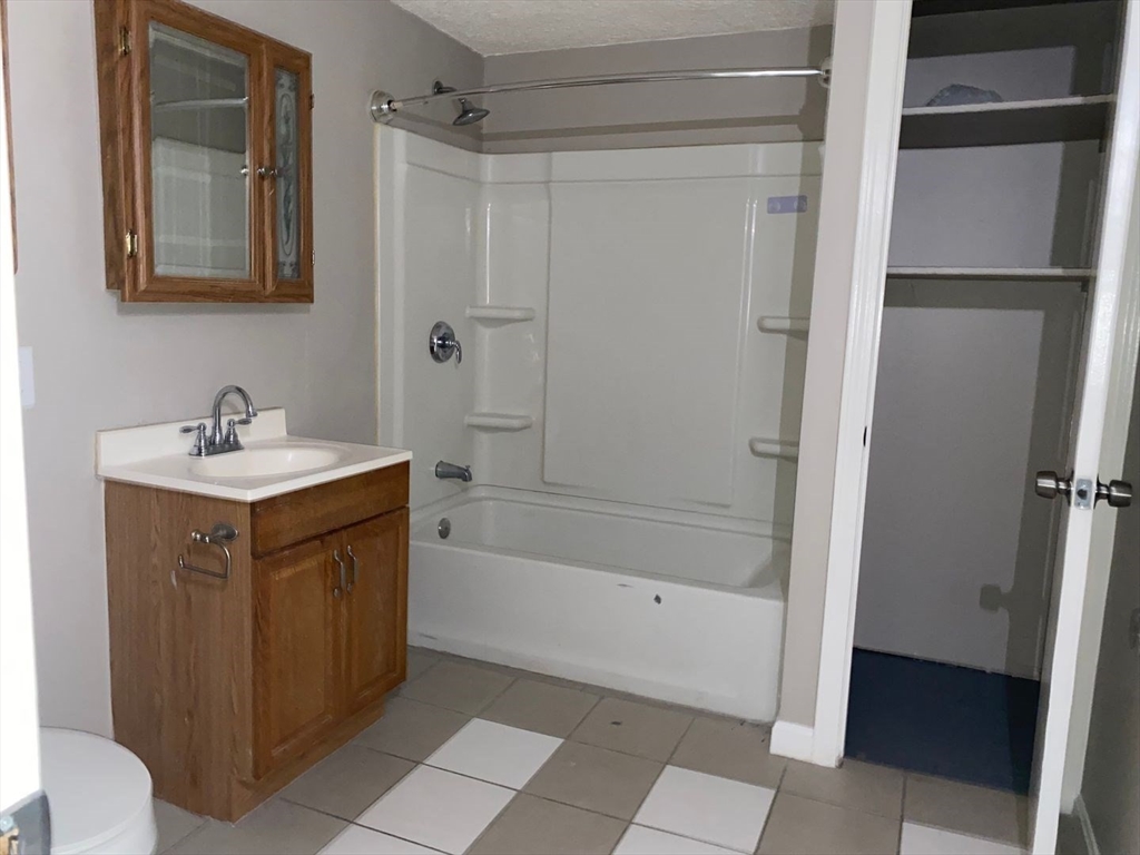 99 Mammoth Road, Unit 2 Lowell, MA 01854 - Photo 6 of 7 a bathroom with a sink a mirror and a bathtub