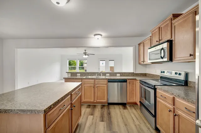 a kitchen with granite countertop stainless steel appliances a sink stove top oven and cabinets