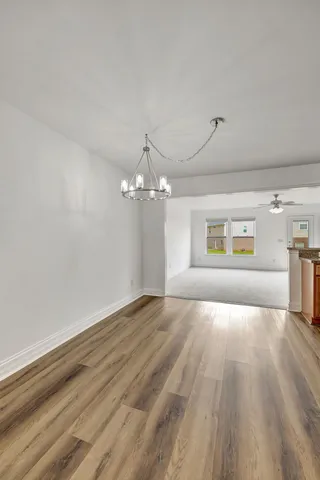 a view of a room with wooden floor chandelier and windows