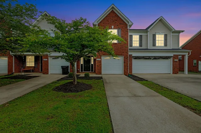 a front view of a house with a garden and trees