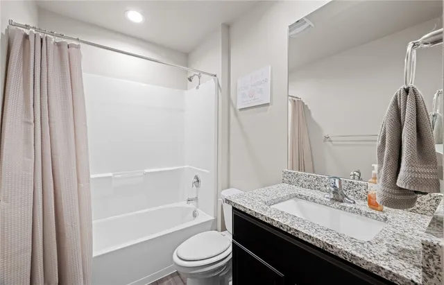 a bathroom with a granite countertop sink toilet and shower