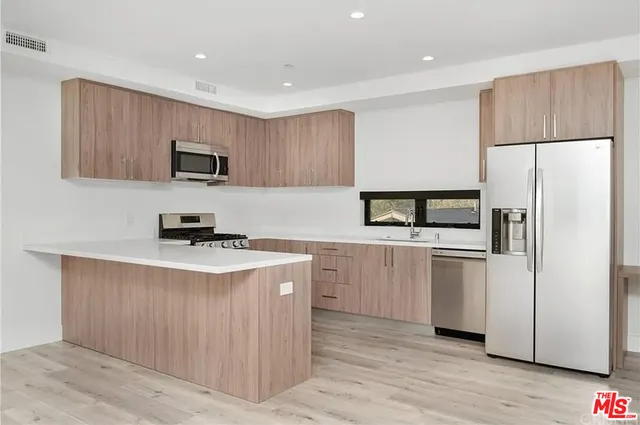 a kitchen with kitchen island a refrigerator stove and microwave