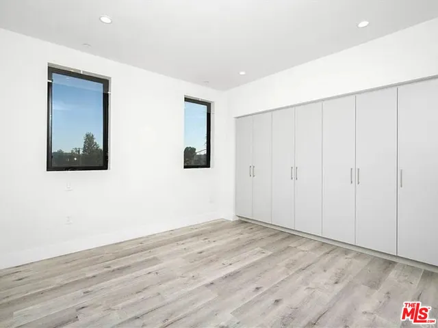 a view of an empty room with wooden floor and closet