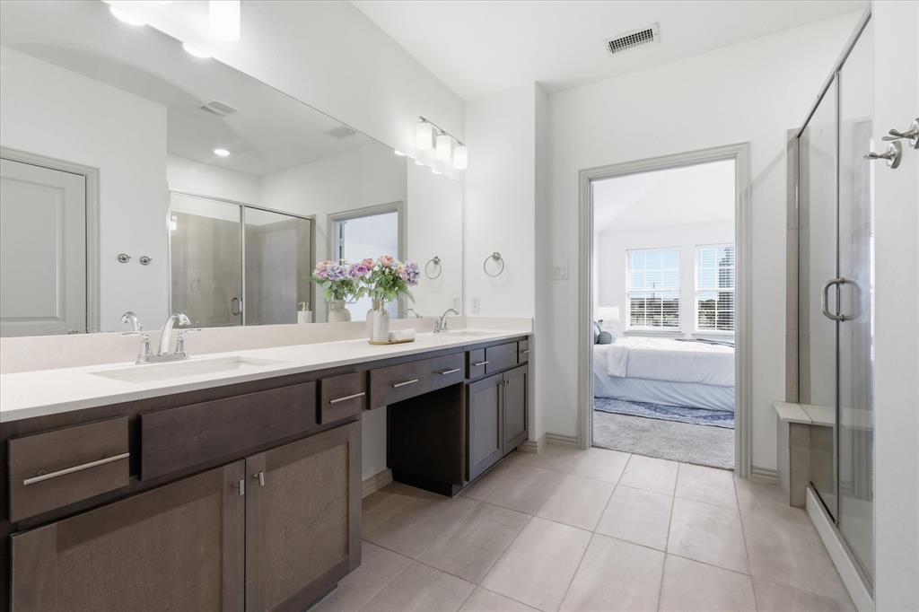6141 Roper Road McKinney, TX 75070 - Photo 23 of 35 Spacious bathroom featuring a dual vanity with light-colored countertops, dark wood-finish cabinetry, and contemporary hardware