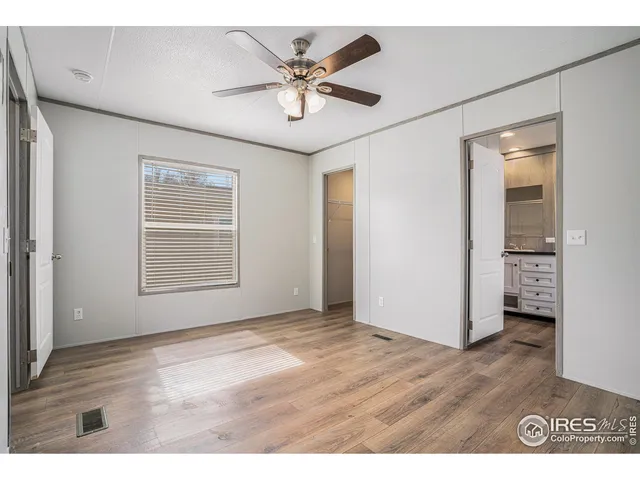 a view of an empty room with wooden floor and a ceiling fan