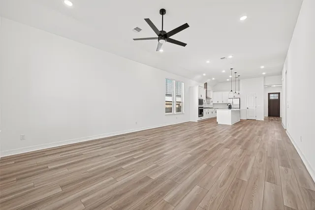 a view of empty room with wooden floor and ceiling fan