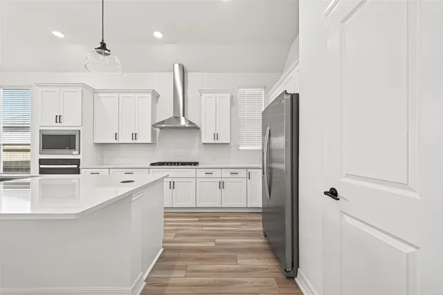 a large kitchen with stainless steel appliances granite countertop a refrigerator a sink dishwasher a stove and white countertops with wooden floor