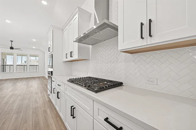 a kitchen with white cabinets and wooden floor