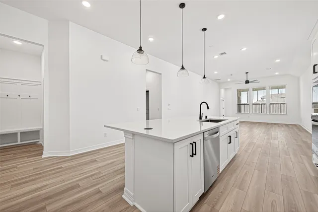 a large kitchen with stainless steel appliances a large center island wooden floor and a sink