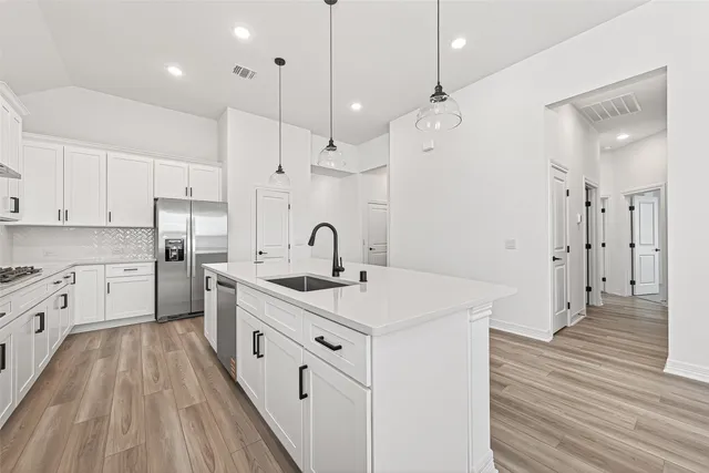 a kitchen with white cabinets appliances and wooden floor
