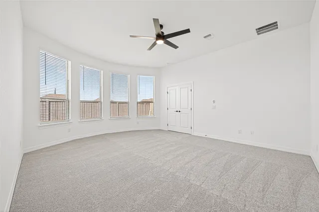 a view of a livingroom with a ceiling fan & windows