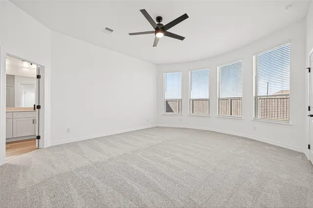 an empty room with chandelier fan and windows
