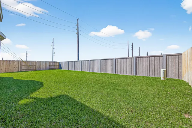 a view of a backyard with grass & fence