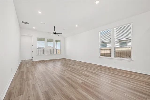 a view of empty room with wooden floor and windows