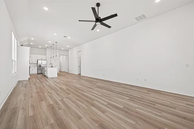 a view of empty room with wooden floor and a ceiling fan