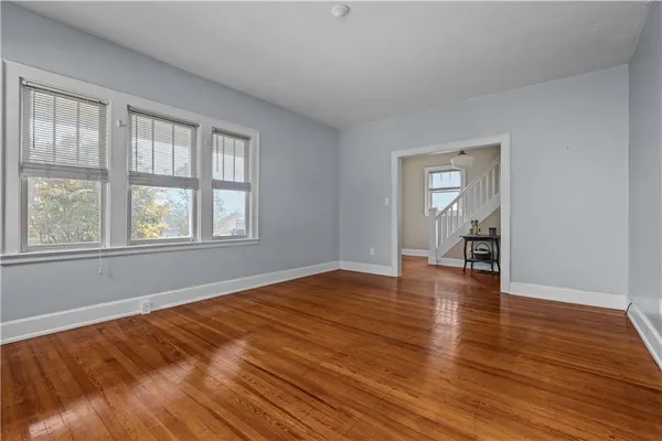 an empty room with wooden floor fireplace and windows