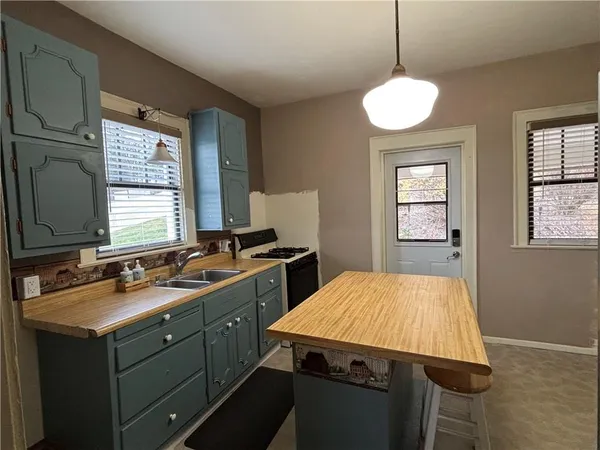 a room with kitchen island stainless steel appliances a sink stove and window
