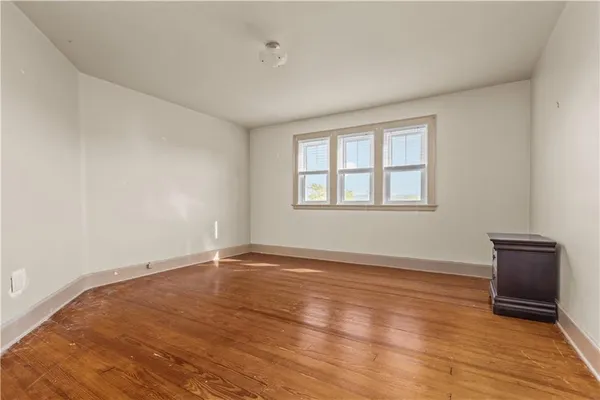 a view of an empty room with window and wooden floor