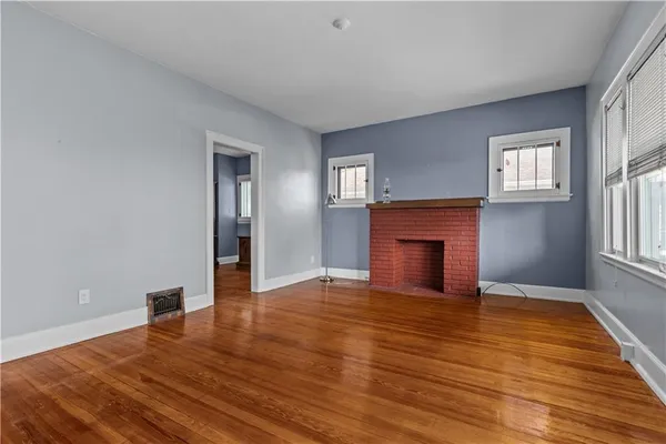 a view of empty room with wooden floor and fireplace