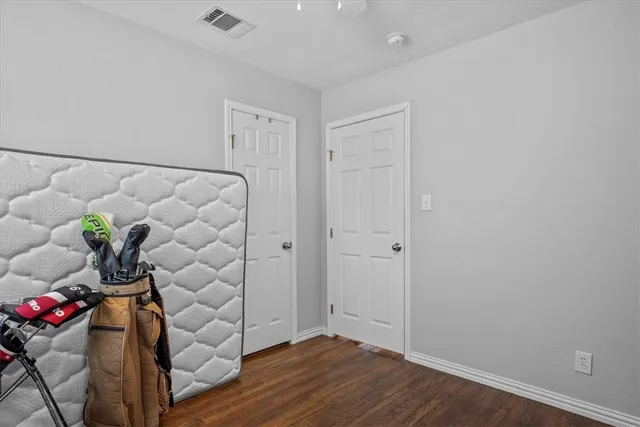 an empty room with wooden floor and a potted plant