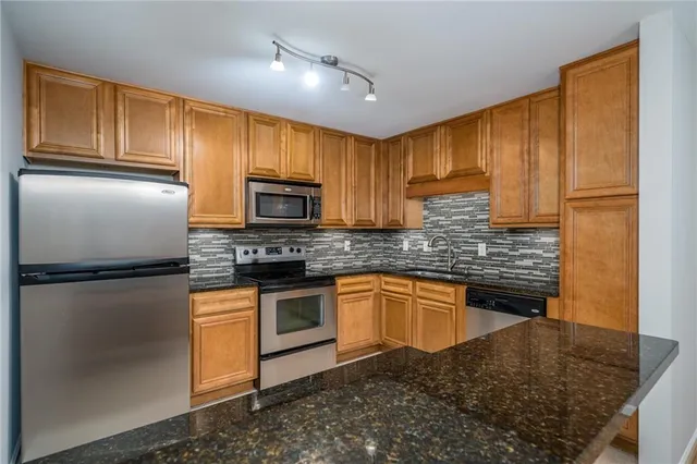 a kitchen with stainless steel appliances granite countertop a refrigerator a stove top oven a sink and dishwasher