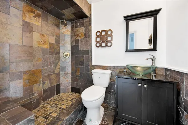 a bathroom with a granite countertop toilet sink and mirror