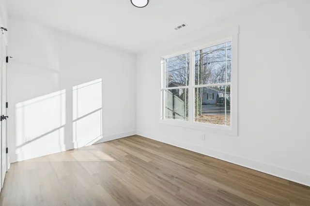 an empty room with wooden floor and windows