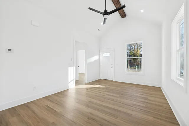 an empty room with wooden floor fan and windows