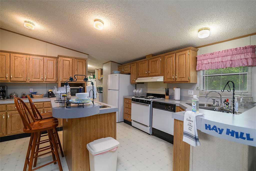 122 Grice Road Ringgold, LA 71068 - Photo 7 of 26 Kitchen with oak cabinetry, laminate countertops, and white appliances