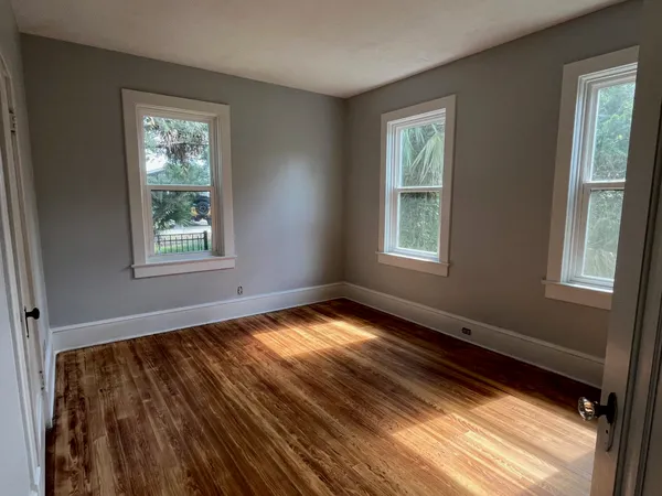 a view of an empty room with wooden floor and a window