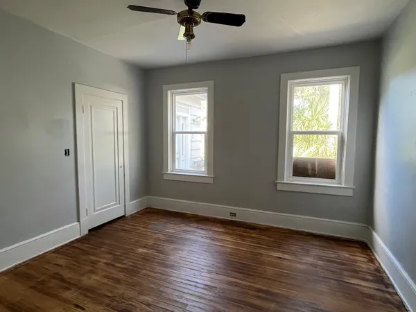 a view of an empty room with wooden floor and a window