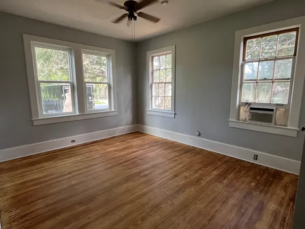 a view of an empty room with a window and wooden floor