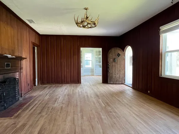 an empty room with windows fireplace and wooden floor