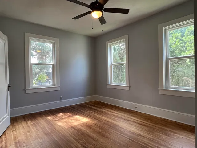 a view of empty room with wooden floor and fan