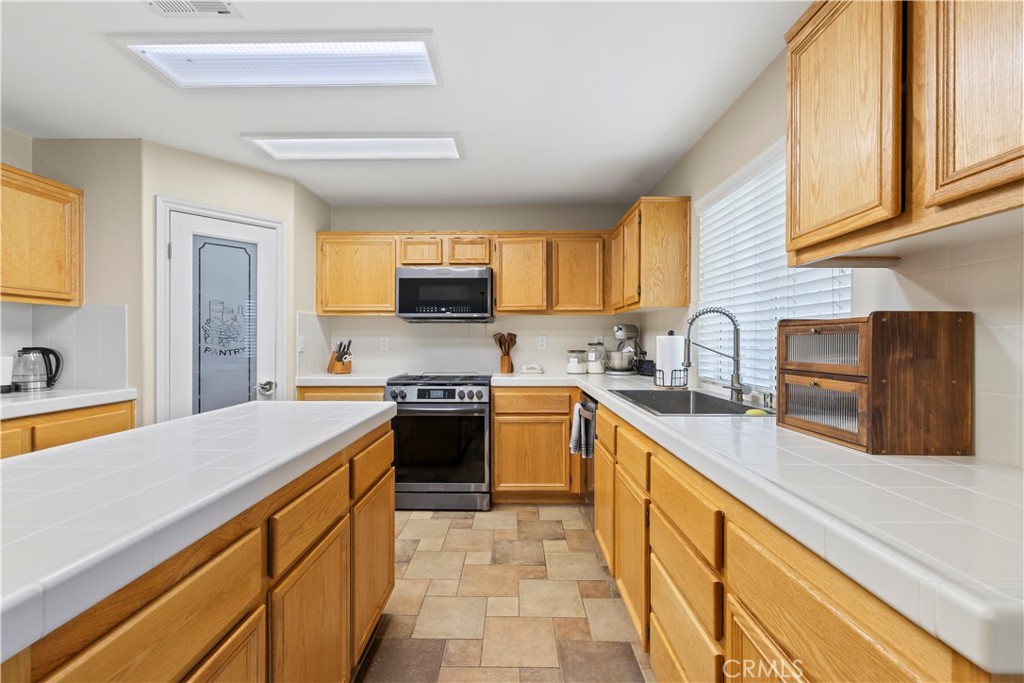 7219 Birch Tree Place Fontana, CA 92336 - Photo 20 of 49 a kitchen with stainless steel appliances a stove sink microwave and cabinets