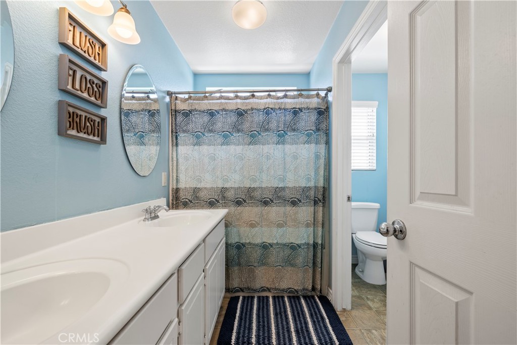 7219 Birch Tree Place Fontana, CA 92336 - Photo 28 of 49 a bathroom with a granite countertop sink a mirror and a shower
