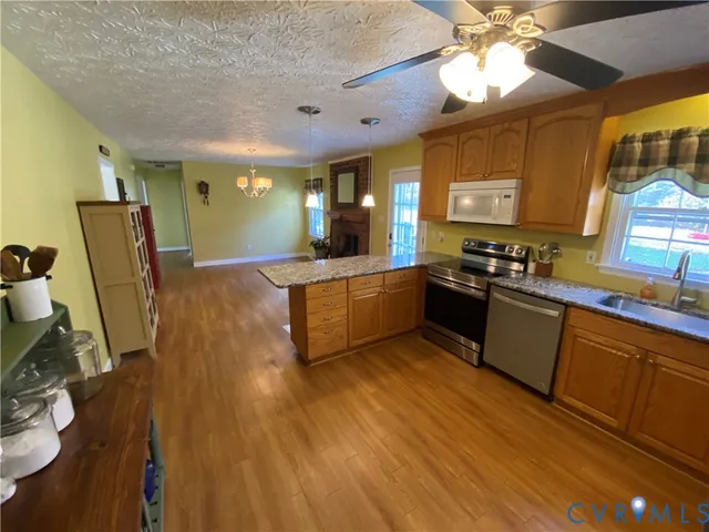 a large kitchen with stainless steel appliances a stove a sink dishwasher and a refrigerator with wooden floor
