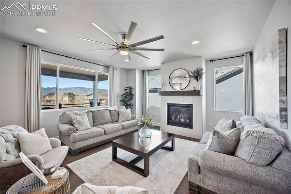 a living room with furniture a fireplace and a large mirror with wooden floor