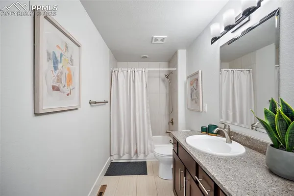 a bathroom with a granite countertop sink a toilet a mirror a vanity and shower