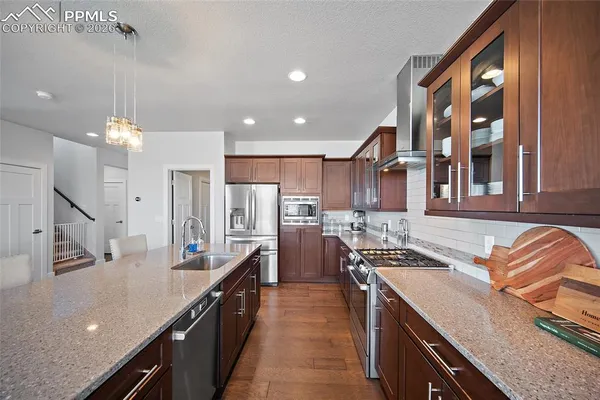 a kitchen with stainless steel appliances a stove a refrigerator a kitchen island and chairs