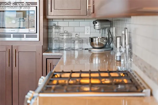 a large white kitchen with a stove a sink a refrigerator and white cabinets with wooden floor