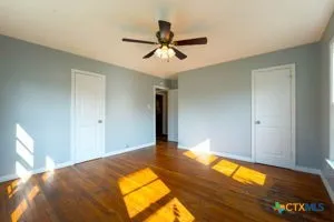 a view of a livingroom with a chandelier fan and wooden floor