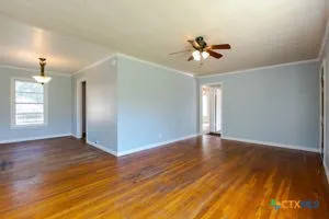 a view of an empty room with window and wooden floor