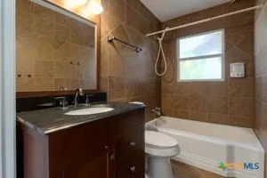 a bathroom with a granite countertop sink toilet and shower