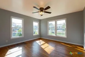 a view of an empty room with wooden floor and a window