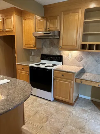 a kitchen with granite countertop a stove top oven sink and cabinets
