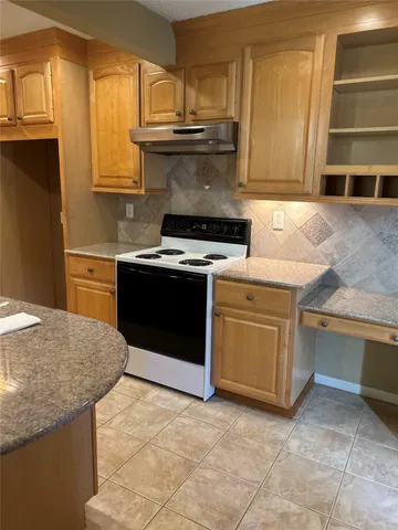 a kitchen with granite countertop a stove top oven sink and cabinets